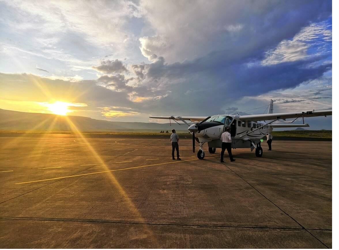 A Cessna Caravan on the apron at sunset while crew prepare it for a charter flight